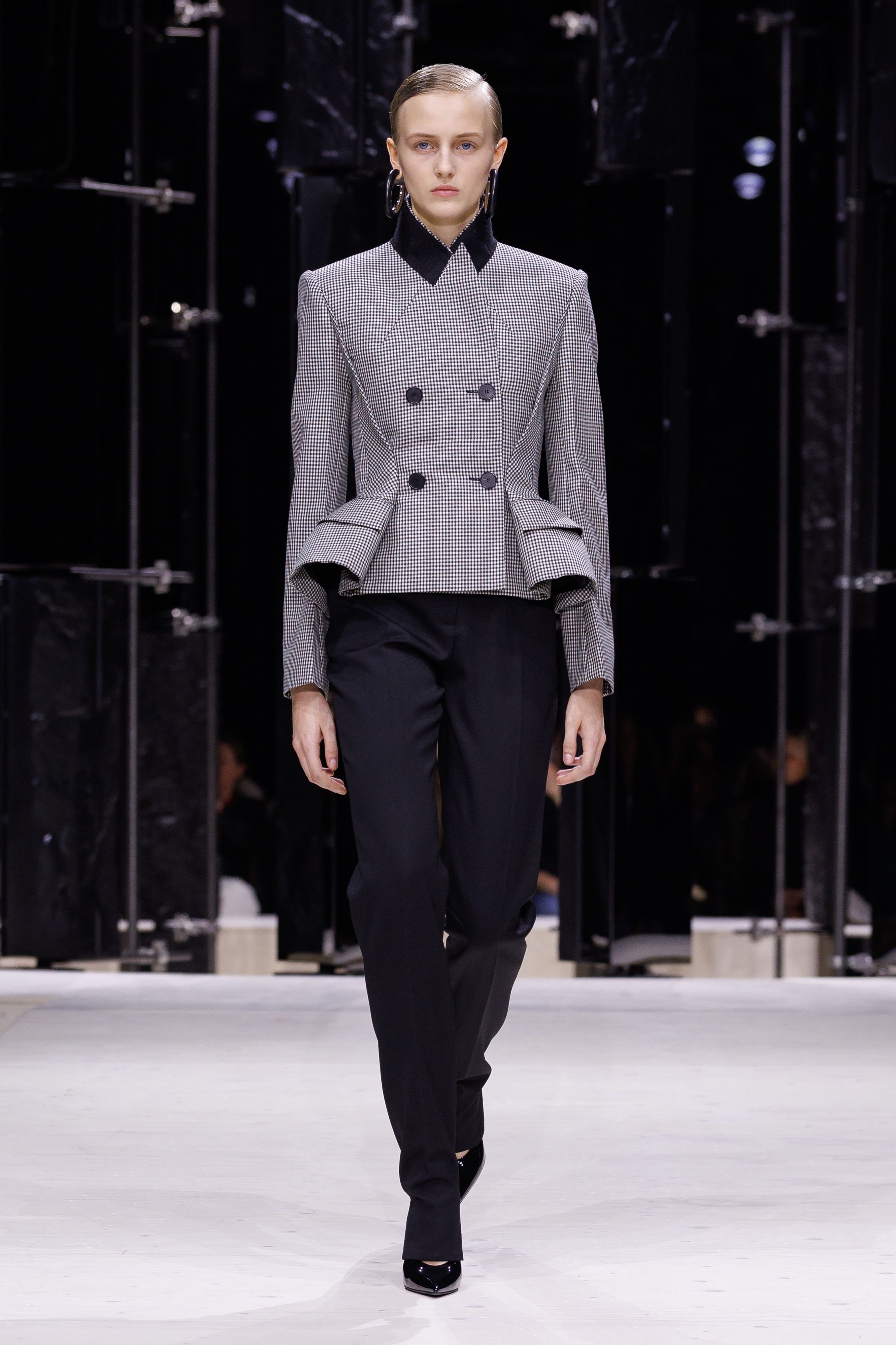 Givenchy 2026秋冬在现代建筑空间中呈现一场充满戏剧性的时装叙事：雕塑式西装、亮色斗篷、结构礼服与夸张装饰共同构建品牌标志性的高级时装气质。蓝色、红色与黄色的高饱和色彩与黑白经典形成鲜明对比，服装通过立体剪裁与夸张廓形展现出强烈视觉张力。整场系列在优雅与戏剧之间取得平衡，展现现代高级时装的力量-顽石频道趋势研究